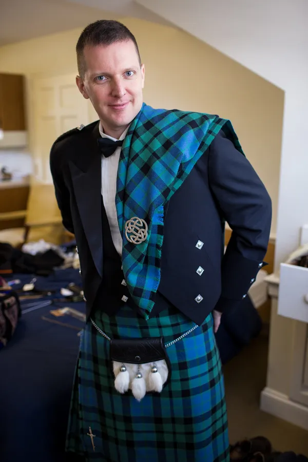 Un hombre vestido con MacDowall Tartan Kilt y una chaqueta escocesa.